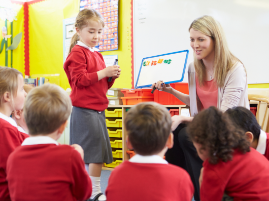 teacher with early years children in red uniform