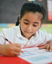 A young pupil sits at their desk, filling out a worksheet.